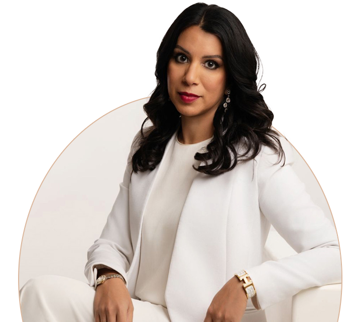 A woman with long dark hair, wearing a white outfit, gazes confidently at the camera with a serious expression.